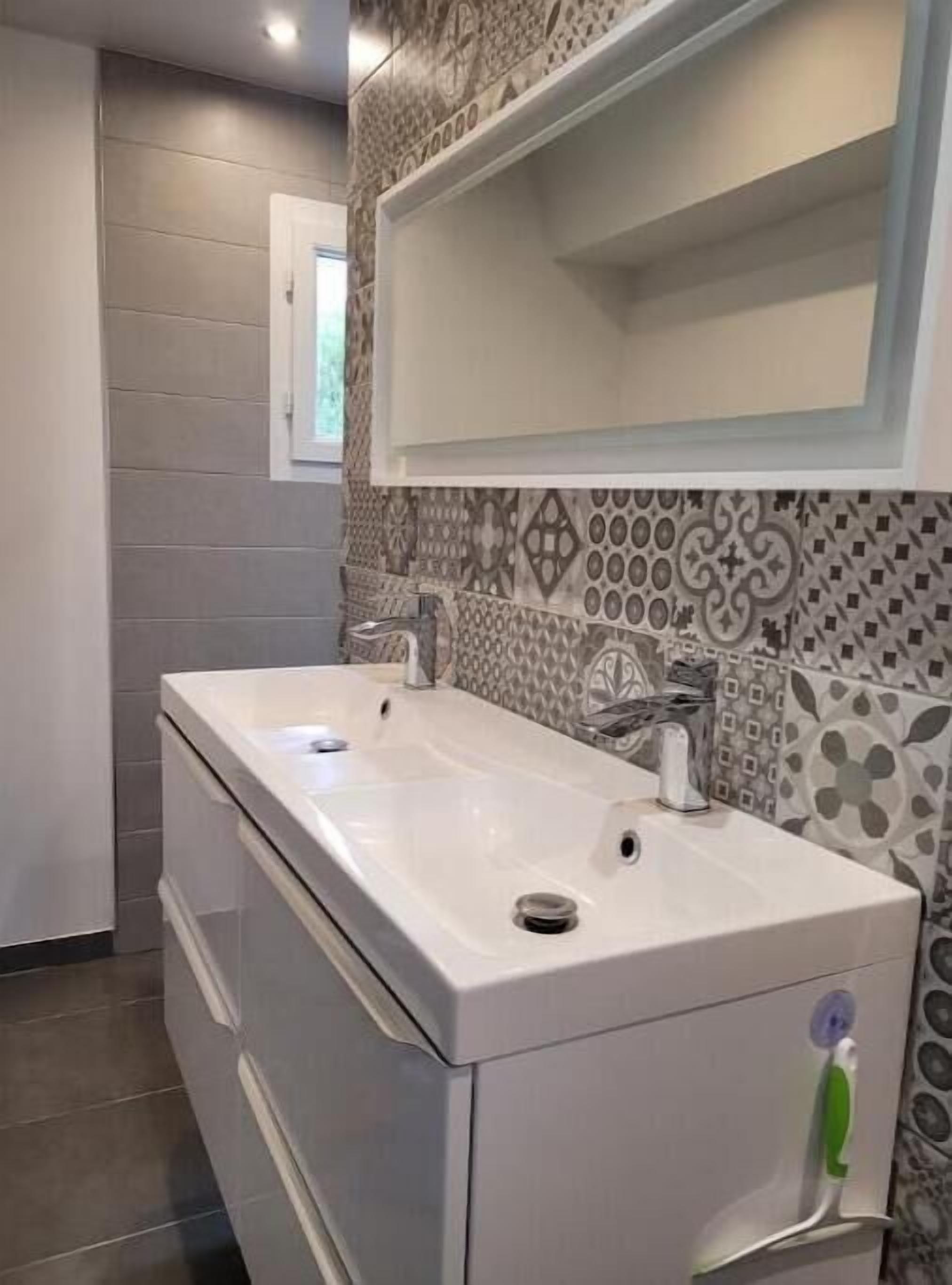 Un baño con dos lavamanos, un espejo y baldosas estampadas.