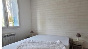 A bedroom with a bed, a window, and a radiator. - Maison Individuelle en Bord de mer (Saint-Martin-en-Campagne)