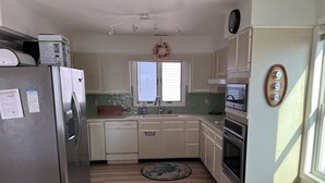 Una cocina equipada con refrigerador, lavavajillas, estufa y un reloj en la pared.