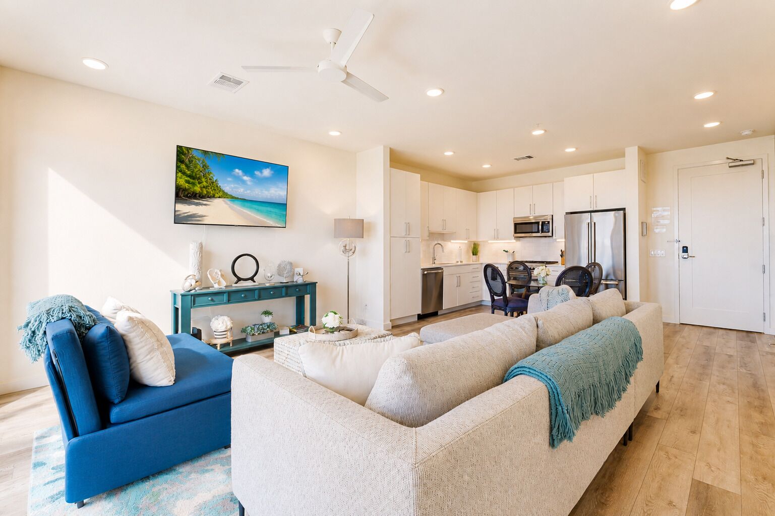 A modern living room with a sofa, a blue armchair, and a dining area with a table and chairs.