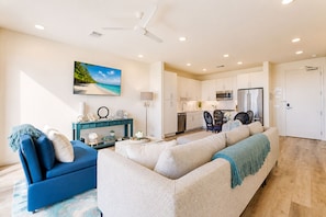 A modern living room with a sofa, a blue armchair, and a dining area with a table and chairs.