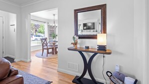 A room with a wooden console table, a large mirror, and a television. - Remodeled home with vintage charm. Centrally located near downtown Idaho Falls. (Idaho Falls)
