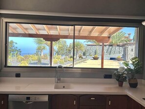 A kitchen with a large window, a sink, and a dishwasher.