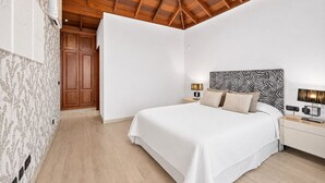 A bedroom with a wooden ceiling, a bed with a zebra-patterned headboard, bedside lamps, and a wardrobe. - Villa in the mountain with views and pool (Adeje)