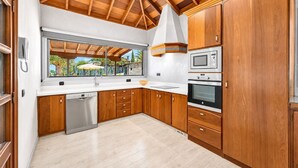 A modern kitchen with wooden cabinets, a built-in oven, a microwave, and a dishwasher. - Villa in the mountain with views and pool (Adeje)