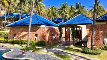 A resort with stone buildings, a swimming pool, and palm trees.