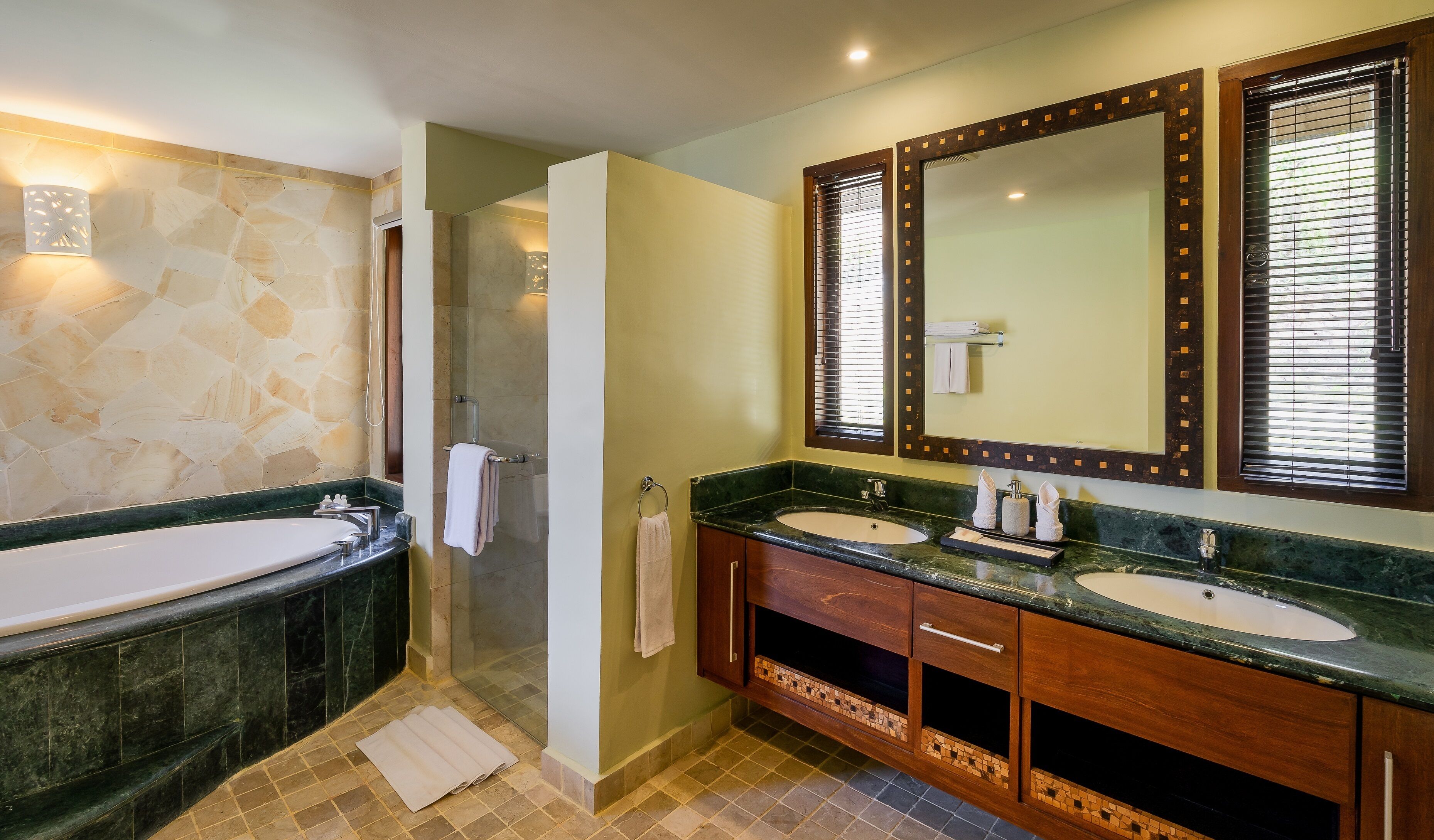 A bathroom with a bathtub, two sinks, a shower, and a large mirror.