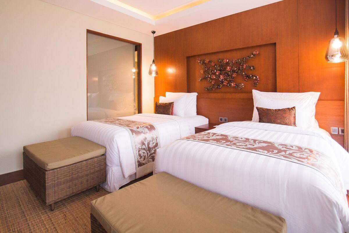 A hotel room with two beds, a large mirror, and a decorative wall piece.