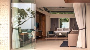 A modern hotel room with a glass sliding door, a bed, a sofa, and a dining area. - Sundancer Residences & Villas Lombok (Sekotong Barat)