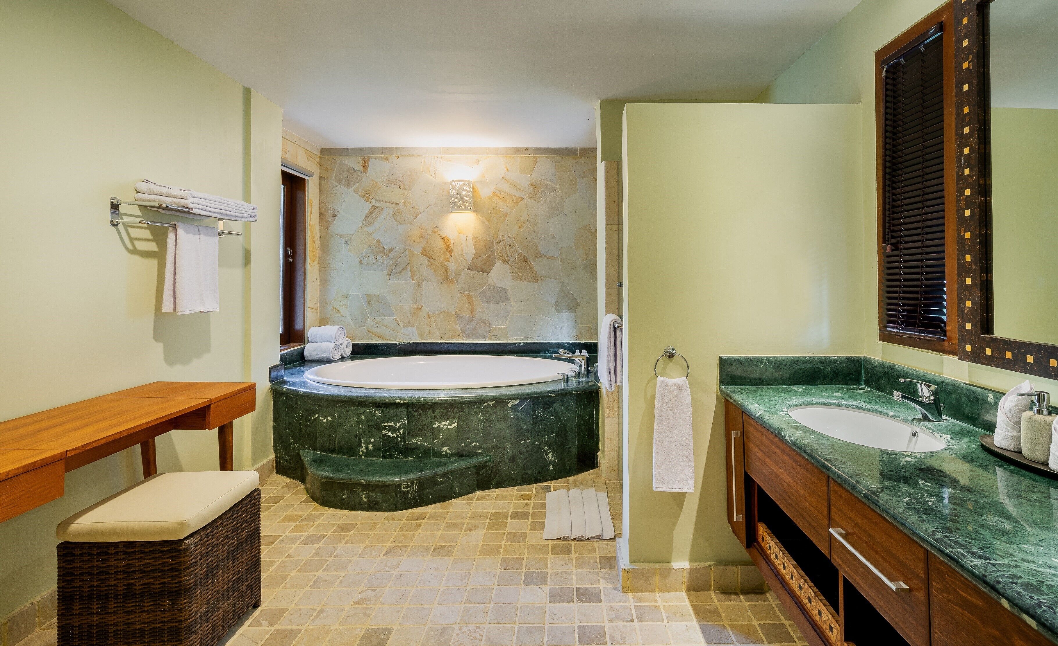 A bathroom with a bathtub, two sinks, a wooden bench, and a wicker basket.