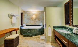 Un baño con bañera, dos lavamanos, un banco de madera y una cesta de mimbre.