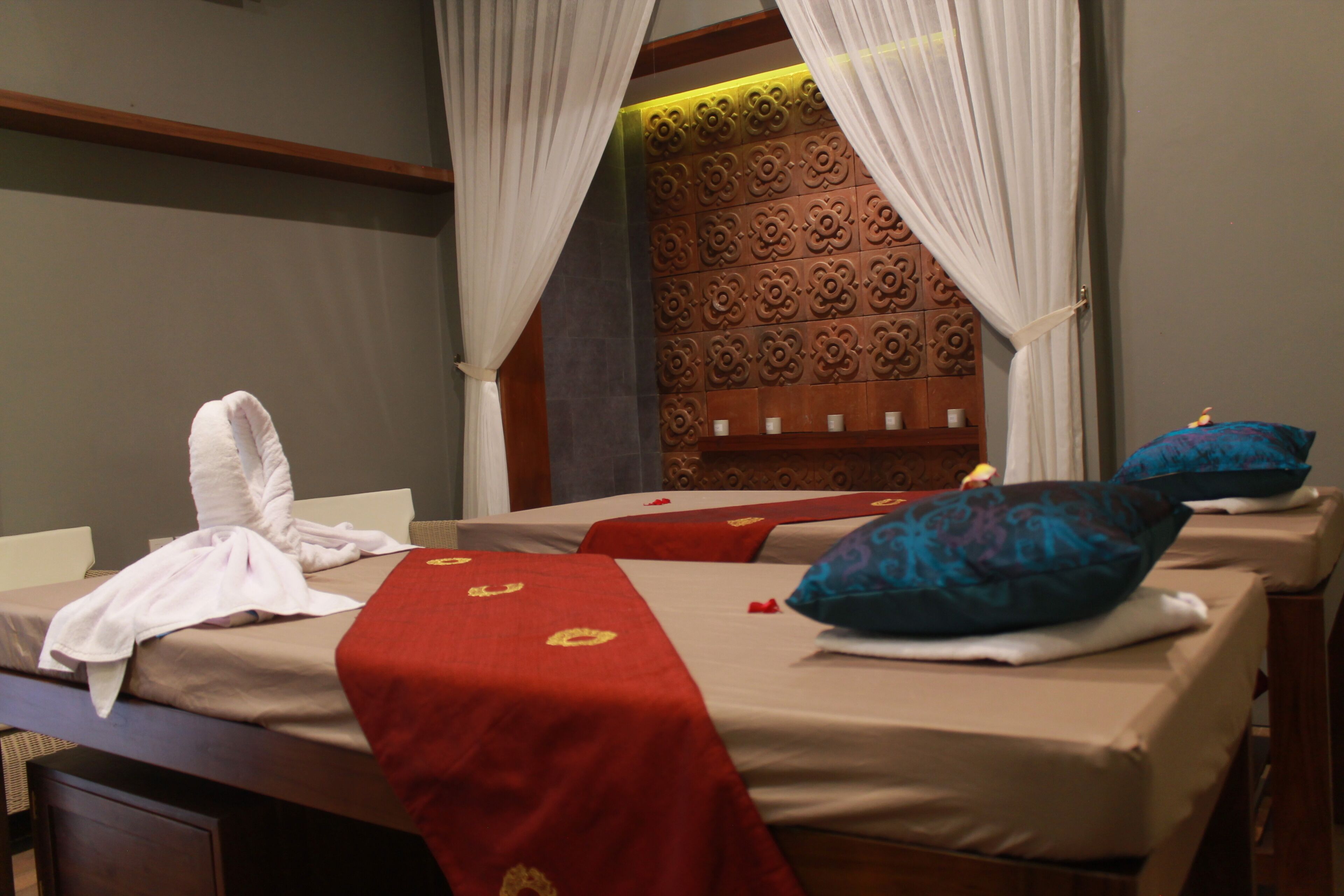 A hotel room with two beds, each with a red bedspread and a white towel.