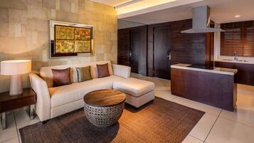 A modern living room with a sofa, a coffee table, and a kitchen area with a countertop and cabinets.