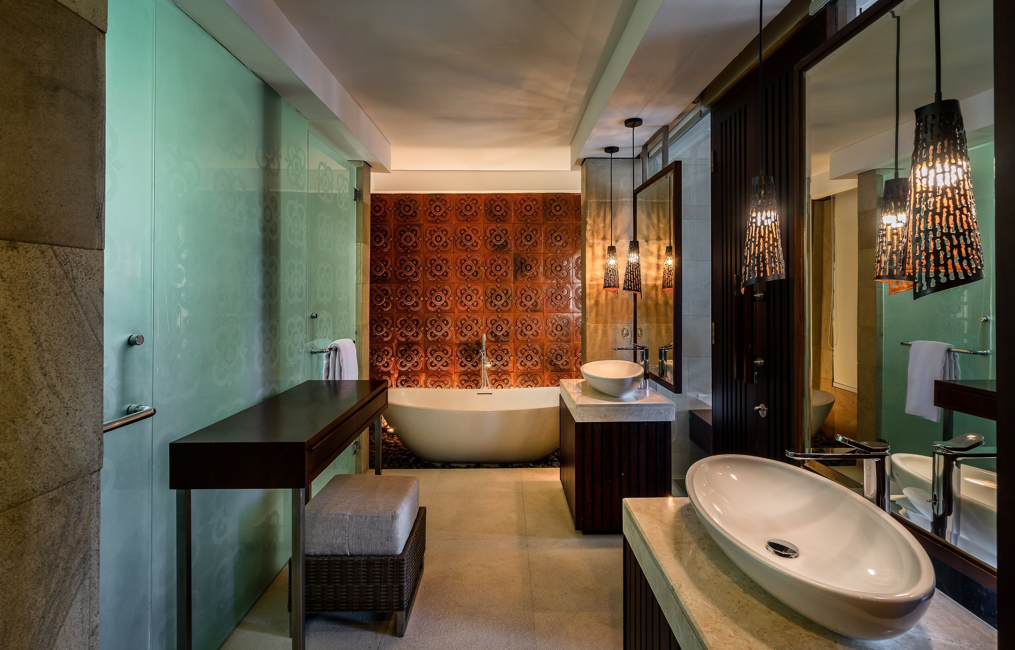 A modern bathroom with a freestanding bathtub, a large vanity with a mirror, and a unique patterned wall.