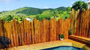 A wooden deck with a swimming pool, surrounded by a wooden fence and a chair. - Villa Kajoane, deluxe villa south of martinique close to beautiful beaches (Fort de France)