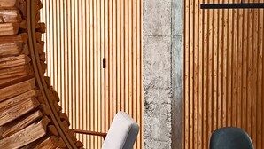 Ein modernes Interieur mit einer runden Holzkonstruktion, einer Betonstütze und einer horizontalen Holzschienenwand.