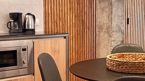 Eine moderne Küche mit Einbauofen, Kaffeemaschine und Essbereich mit rundem Tisch und zwei Stühlen.