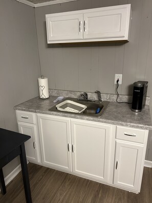 Kitchen area with sink, coffee maker, and table.