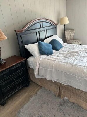 Cozy retreat with a plush bed, nightstand, and comfortable chair.
