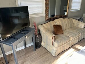 Relax in this stylish living room with a flat-screen TV, ornate mirror, and comfortable sofa.