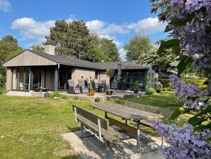 Een modern huis met een patio, zitplaatsen buiten en een tuin.