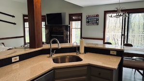 A kitchen with a stone fireplace, a large window, and a sign indicating nearby locations. - Beautiful Camelback Views, Mountain - New Renovated 3-Bed / 2-bath home (Tannersville)