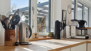 Una cocina con cafetera, hervidor y utensilios sobre la encimera.