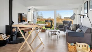 Una sala de estar con una mesa de madera, un sofá, un sillón, un televisor y una chimenea.