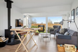 A living room with a wooden table, a sofa, a chair, a TV, and a fireplace.