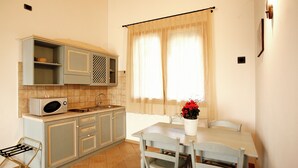 A compact kitchen with a microwave, sink, and cabinets. There is a dining table with chairs and a potted plant. - STUDIO APARTMENT A FEW KM FROM THE BEACH OF CESENATICO (cesenatico)
