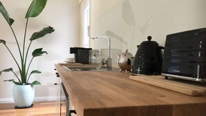 Une cuisine avec un plan de travail en bois, une machine à café, une bouilloire et une plante en pot.