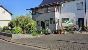 Et toetagers hus med have, en terrasse med udendørs møbler, og et solpanel på taget.