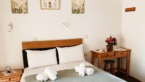 Una cama bien hecha con una colcha verde, un cabecero de madera y dos cuadros colgados en la pared.
