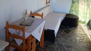Una habitación acogedora con techo de madera, una cama, una mesa con sillas, un televisor y un ventanal con cortinas.