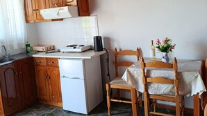 Una cocina con armarios de madera, un refrigerador blanco, una estufa y una mesa de comedor con sillas.
