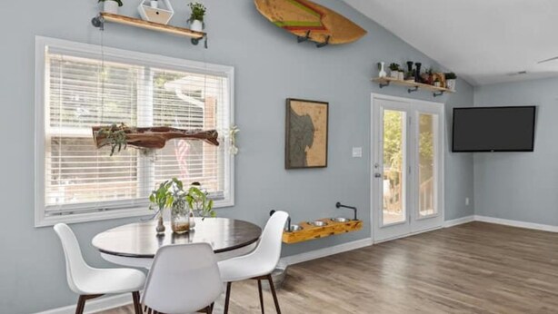 Un espace repas avec une table ronde, des chaises blanches et un plancher en bois.