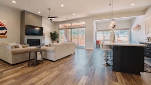A spacious living room with a large TV, two sofas, and a wooden floor. - New Build in Heart of Sedona (Sedona)