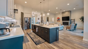 A modern kitchen with a central island, stainless steel appliances, pendant lighting, and a hardwood floor. - New Build in Heart of Sedona (Sedona)