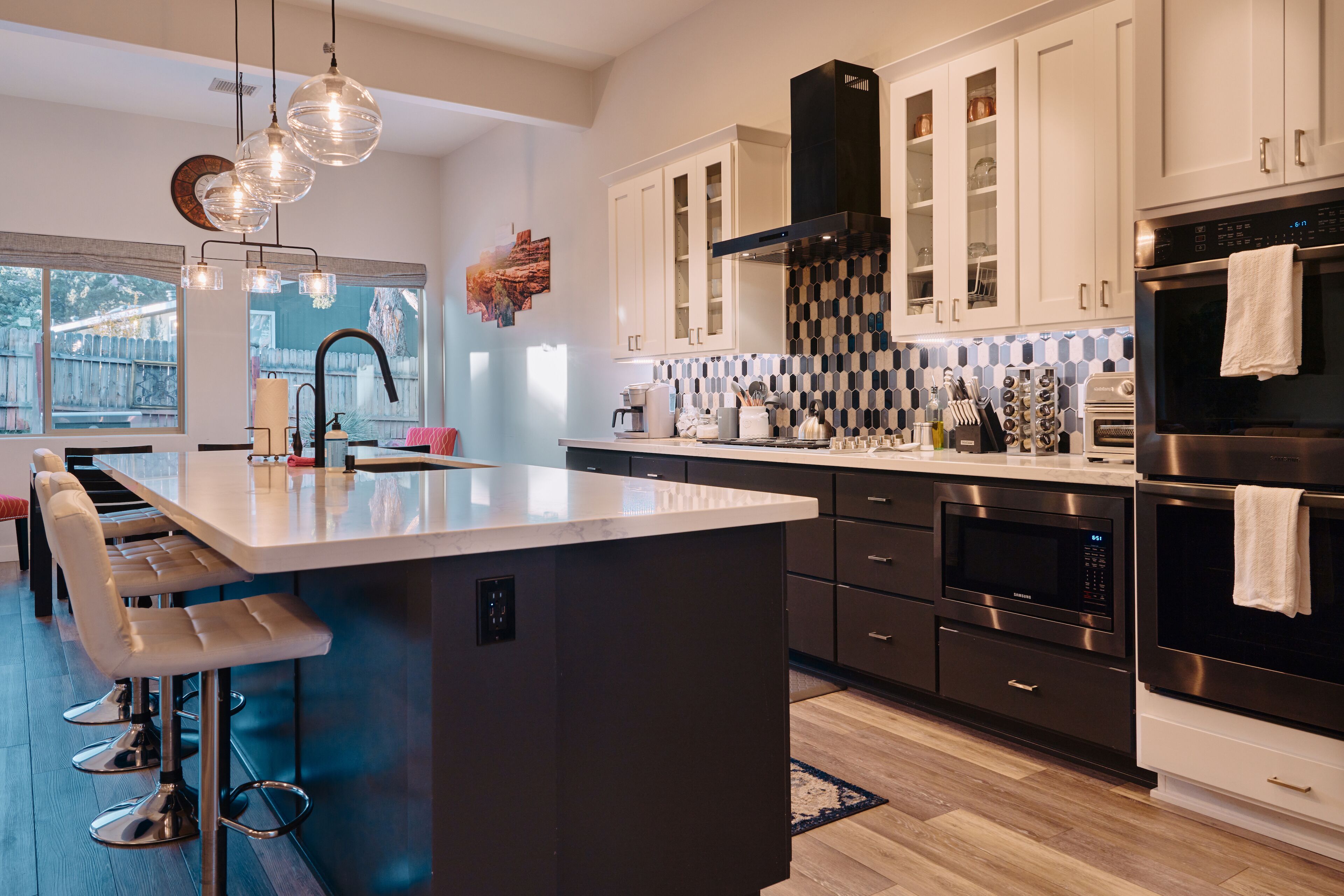 A modern kitchen with a central island, stainless steel appliances, and a large window.