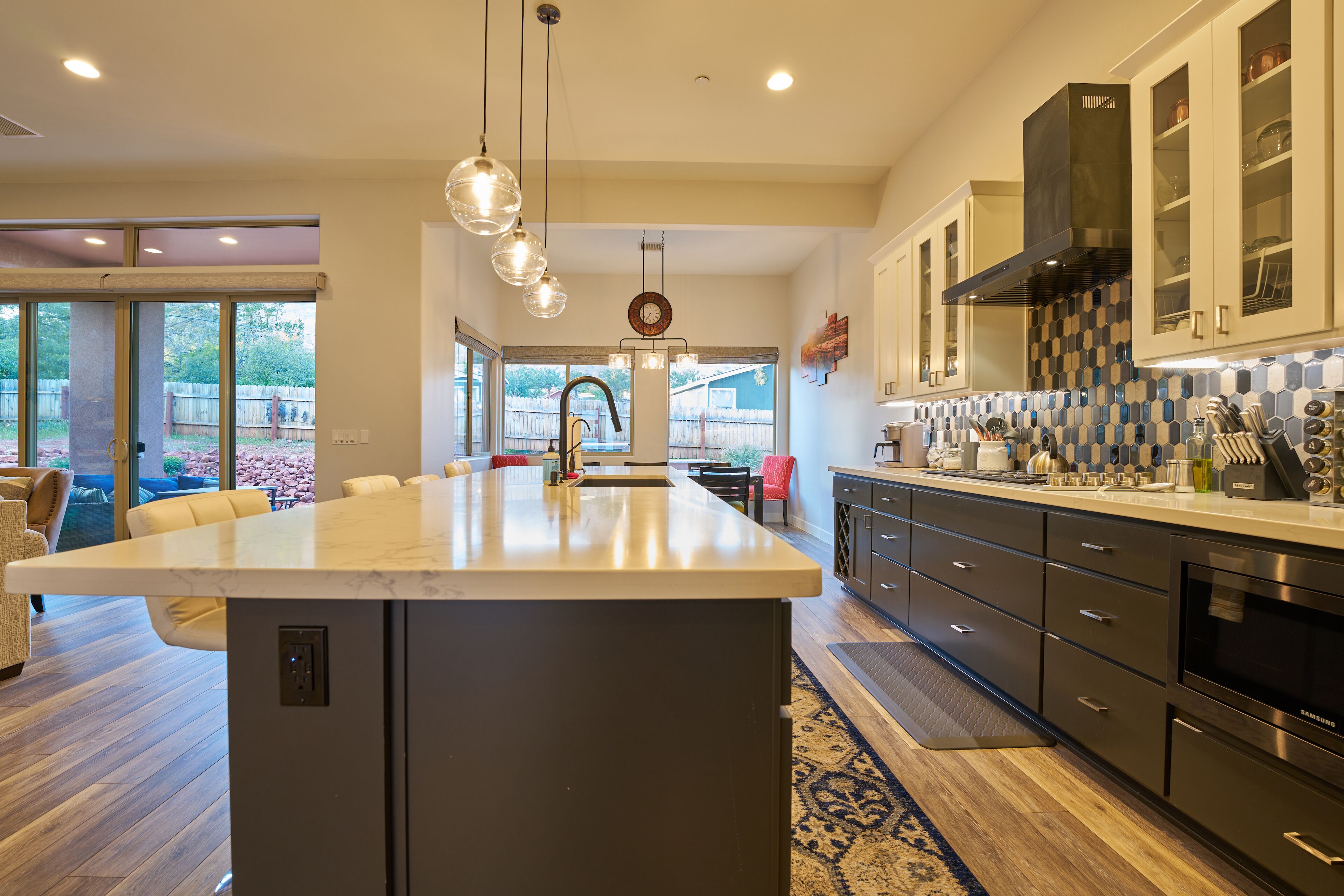 A modern kitchen with a large island, stainless steel appliances, and a view to the backyard.
