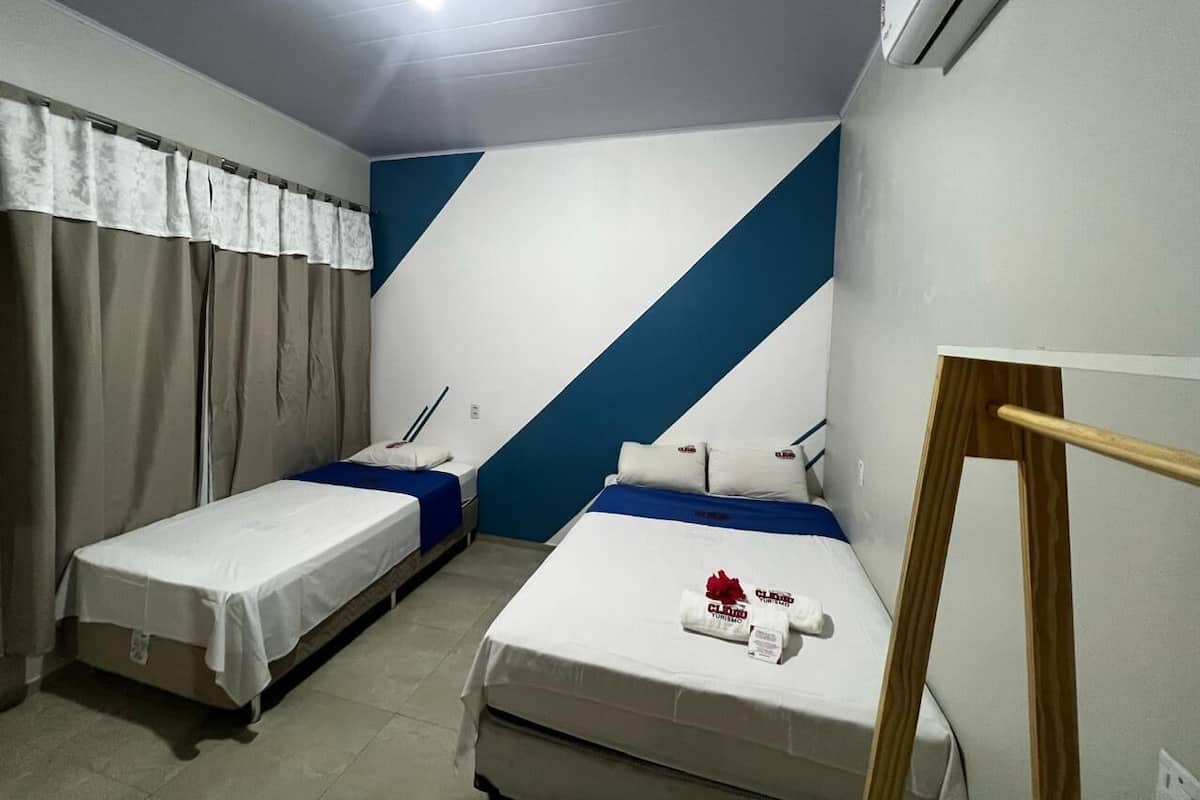 A hotel room with two single beds, a wooden easel, and a ceiling fan.