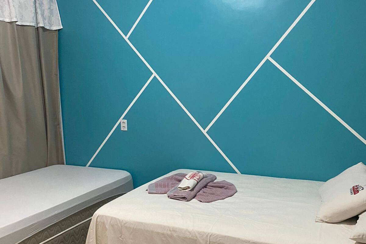 A room with a bed, a smaller bed or couch, and a wall with a geometric pattern.