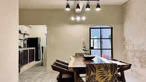 Zona pranzo con tavolo e sedie in legno, pavimento decorato e vista sulla cucina.