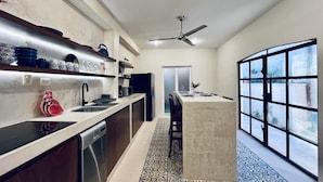 Una cucina moderna con lavastoviglie integrata, un'isola ampia con lavello e una ventola a soffitto.