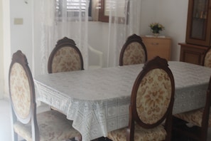 A dining table with a lace tablecloth, surrounded by four upholstered chairs with floral patterns.