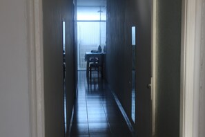 A narrow hallway with a table and chairs in the distance.