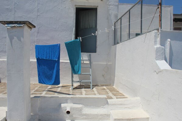 A white building with a laundry area featuring a clothesline with two blue towels.