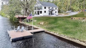 Ein Haus mit einem Steg, der in einen Fluss führt, einer amerikanischen Flagge und einer Rasenfläche.