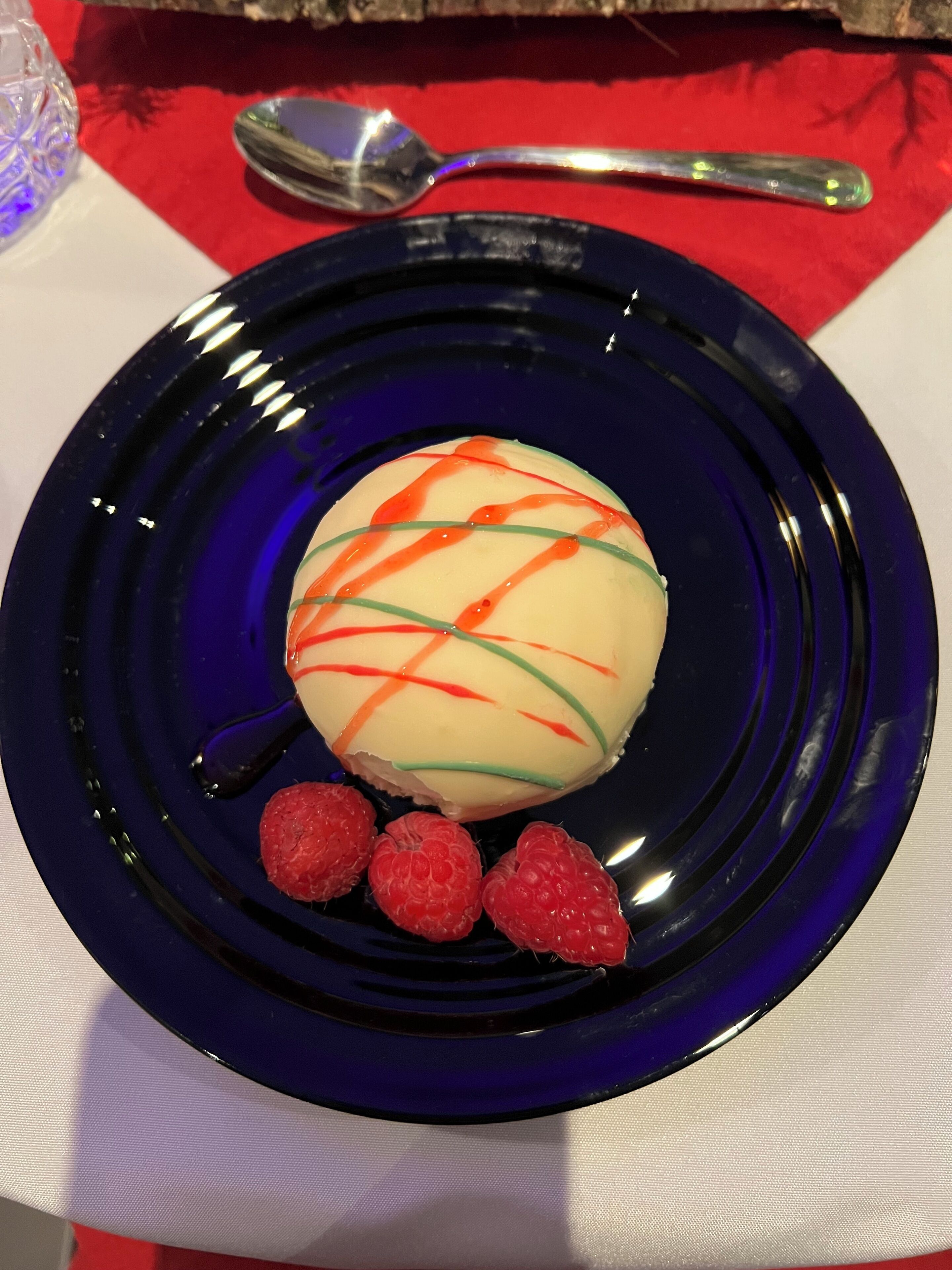 Dessert op een blauw bord, met een lepel en een glas op de achtergrond.