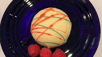 Dessert op een blauw bord, met een lepel en een glas op de achtergrond.